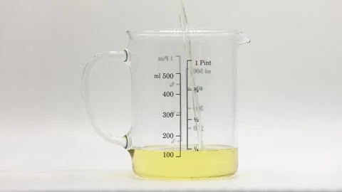 Melted candle wax being poured into glass measuring jug Stock Footage 344743077