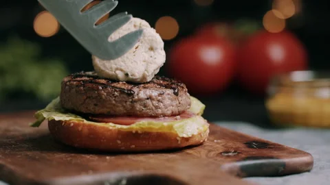 Melted Cheese Being Placed On Hamburger Bun  With Tomato and Lettuce Video stock 134412008