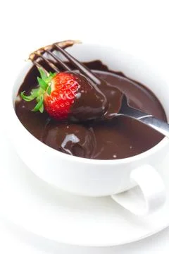 Melted chocolate in a cup, fork and strawberries isolated on white Stock Photos
