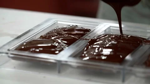 Melted chocolate poured into molds to make chocolate bars Stock Footage 307013083