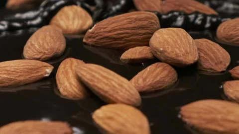 Melted chocolate pouring on almond nuts slow motion extreme close up Stock Footage