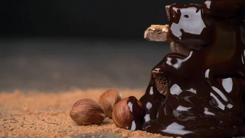 Melted chocolate pouring over heap of broken pieces chocolate and nuts Stock Footage