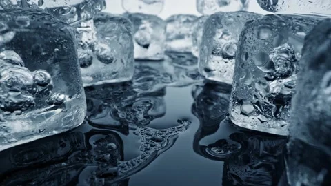 Melted ice cubes close up. Camera moves through ice cubes with water drops over Video stock 230979953