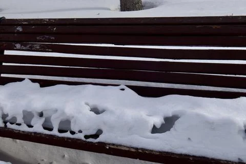Melted snow on a bench on the eve of spring Stock Photos