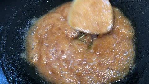 Melted sugar boils in a pan over medium heat stove Stock Footage 244637529
