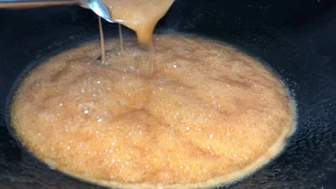 Melted sugar boils in a pan over medium heat stove Stock Footage 244640417