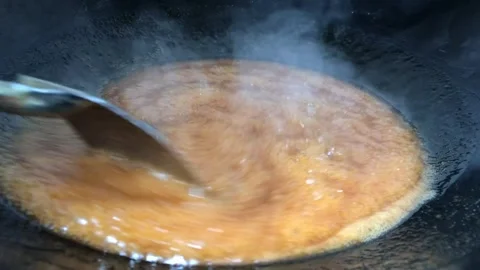 Melted sugar boils in a pan over medium heat stove Stock Footage 244640419