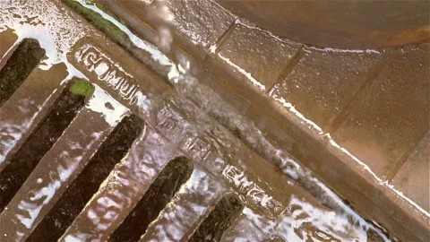 Melted water flows down through the manhole cover on a sunny spring day. Stock Footage 106118399