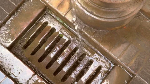 Melted water flows down through the manhole cover on a sunny spring day. Stock Footage 106118430
