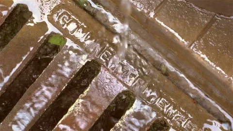 Melted water flows down through the manhole cover on a sunny spring day. Stock Footage 106118471