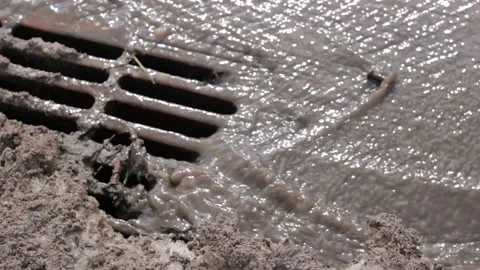 Melted water flows down through the manhole cover Stock Footage 113359819