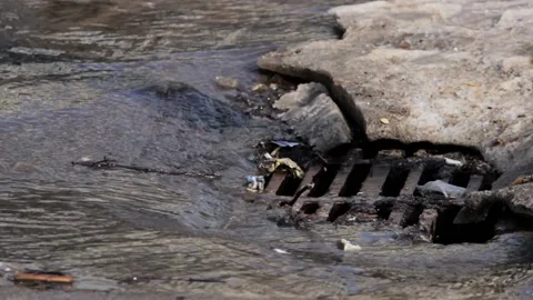 Melted water flows down through the manhole cover Stock Footage 120413604