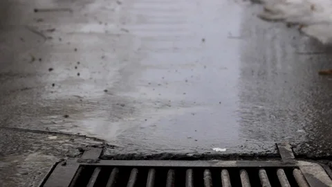 Melted water flows down through the manhole cover Stock Footage 121669346