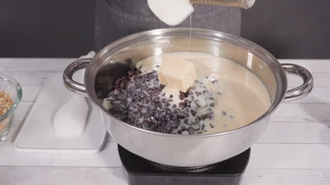 Melting chocolate chips in the cooking pot to make macadamia nut fudge. Stock Footage 130931915