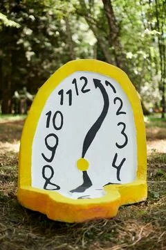 Melting clock art object lying on forest ground outdoor art exhibition, atm.. Stock Photos
