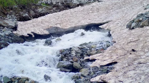 Melting of the glacier. Mountain Stream flowing Under Ice Stock Footage 65573482