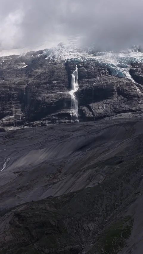 Melting glacier waterfall cascading down rocky mountain cliff Stock Footage 318010797