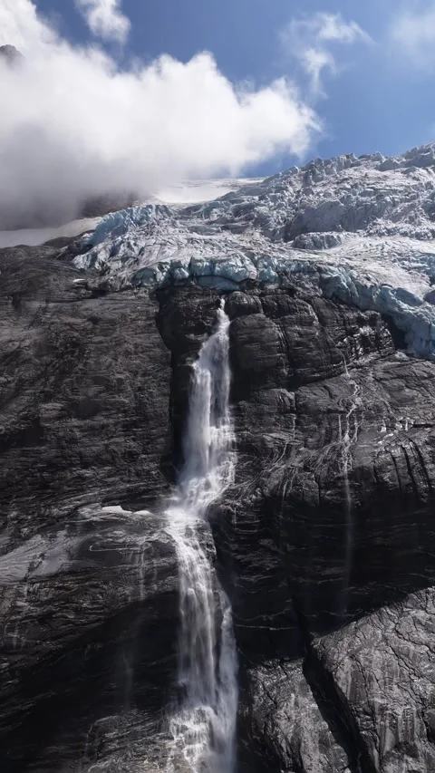 Melting glacier waterfall cascading down a rocky mountain cliff Stock Footage 318011025