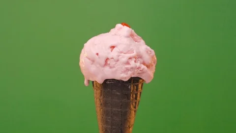 Melting Ice cream in dark cone with strawberry topping on a green background Stock Footage 109058185
