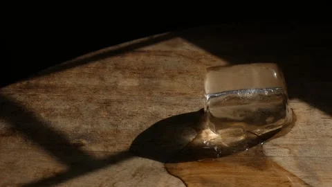 Melting ice cube on rustic wooden table surface 스톡 동영상 337873164