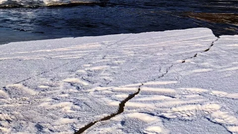 Melting ice floe cracking and drifting down a flowing river in late winter Stock Footage 346594403