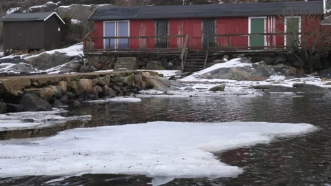 Melting ice floe floating close to a stone pier, bath cabin in background Stock Footage 150086805