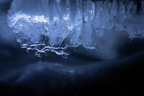 Melting Ice Formations Hover Over Dark Flowing Water in Mysterious Winter Sce Stock Photos