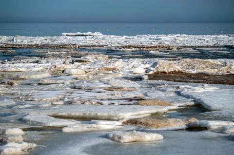 Melting ice forms floating on water in a coastal area during the early mornin Stock Photos
