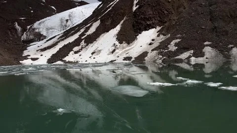 Melting ice on remote alpine lake below snowy mountains in Kazakhstan Stock Footage 341801831
