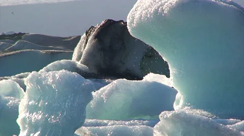 Melting iceberg dripping while smaller icebergs drift by in front 스톡 동영상 37913104