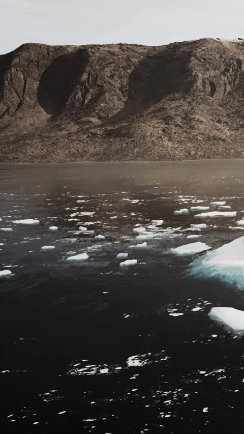 Melting icebergs float in dark water near rocky cliffs in a remote area Stock Footage 337926062