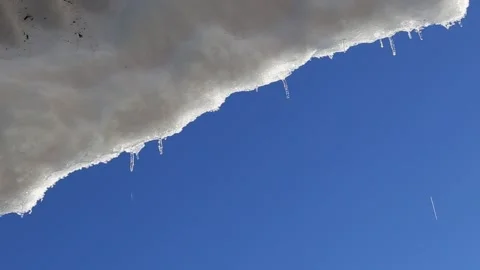 Melting icicles with the blue sky and sun in the background Stock Footage 188970937