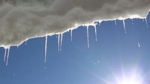 Melting icicles with the blue sky and sun in the background Stock Footage 188978092