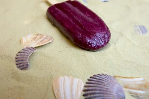 Melting popsicle on sand with shells Foto stock