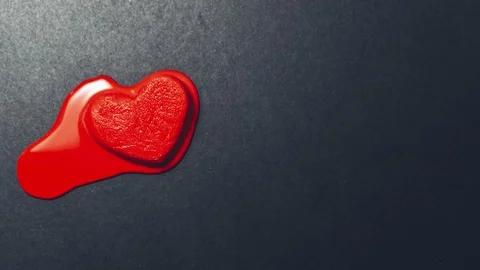 Melting red heart shape ice cream on dark or black textured paper background Stock Footage 93513605