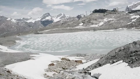Melting snow creating a small stream flowing into the frozen riffelsee lake Stock Footage 339212903