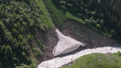 Melting snow narrowing river flow in mountain valley Video stock 312444283