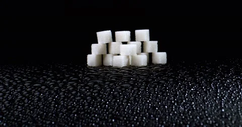 Melting sugar pyramid on black surface with shiny water droplets. Unhealthy wall Stock Footage 149690239