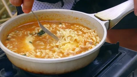 Melting two sticks of butter in a pan of ramen noodles and stirred with a fork Stock Footage 346122269