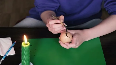 Melting the wax over the candle, with the help of a pen, the girl puts a pattern Stock Footage 234711064