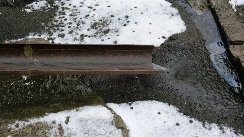Meltwater flows through a storm drain pipe . Concept of the onset of spring,  Stock Footage 125167878