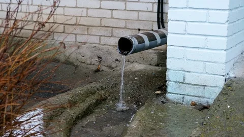 Meltwater flows through a storm drain pipe . Concept of the onset of spring,  Stock Footage 125175090