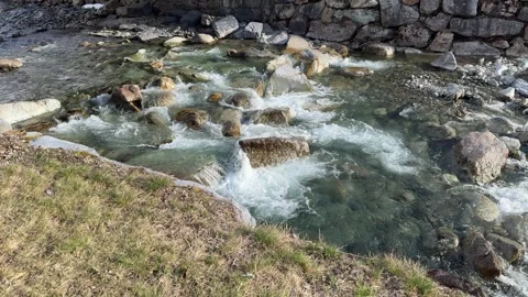 A meltwater river flows over the rocks in a Swiss village Stock Footage 306147259