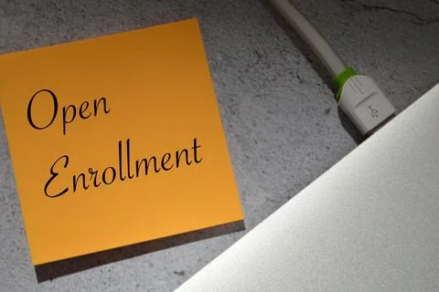 Memo note written with text OPEN ENROLLMENT over grey background. Stock Photos