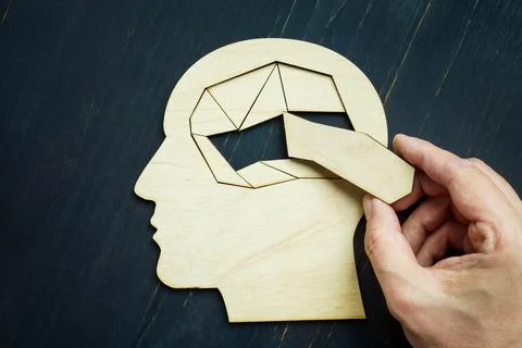 Memory loss and problems with brain. The hand puts the last piece of the puzzle. Stock Photos