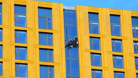 Men abseiling down building cleaning office and apartment windows uk Stock Footage 126211441