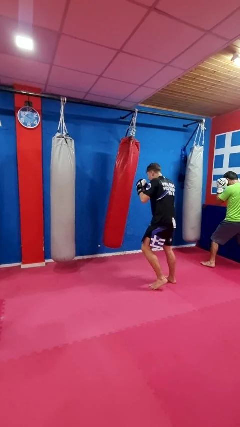 Men and boy training kickboxing on heavy punching bags in a martial arts gym in Stock Footage 332742409