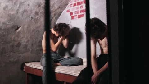 Men are imprisoned behind bars and a man tries to commit suicide with a bag on Stock Footage 159698297