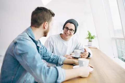 Men are sitting in front of the table near window Stock Photos