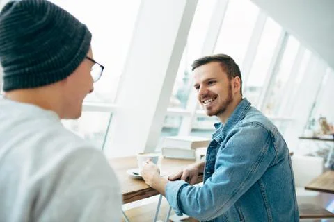 Men are sitting in front of the table near window Stock Photos